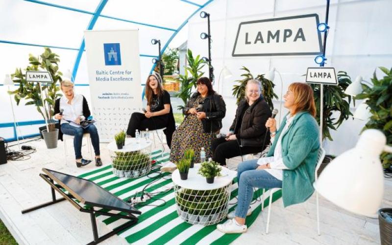 Āra paneļdiskusija, kurā piecas sievietes sēž un iesaistās sarunā. Vidē ir augi, LAMPA izkārtne un Baltijas Mediju izcilības centra baneris.